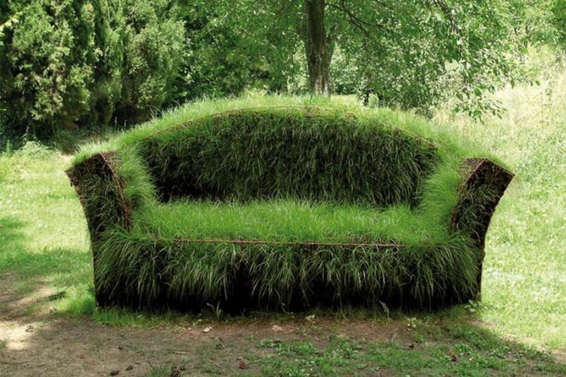 Divano naturale ricoperto d’erba in un giardino d’artista, perfettamente integrato nel paesaggio verde circostante.